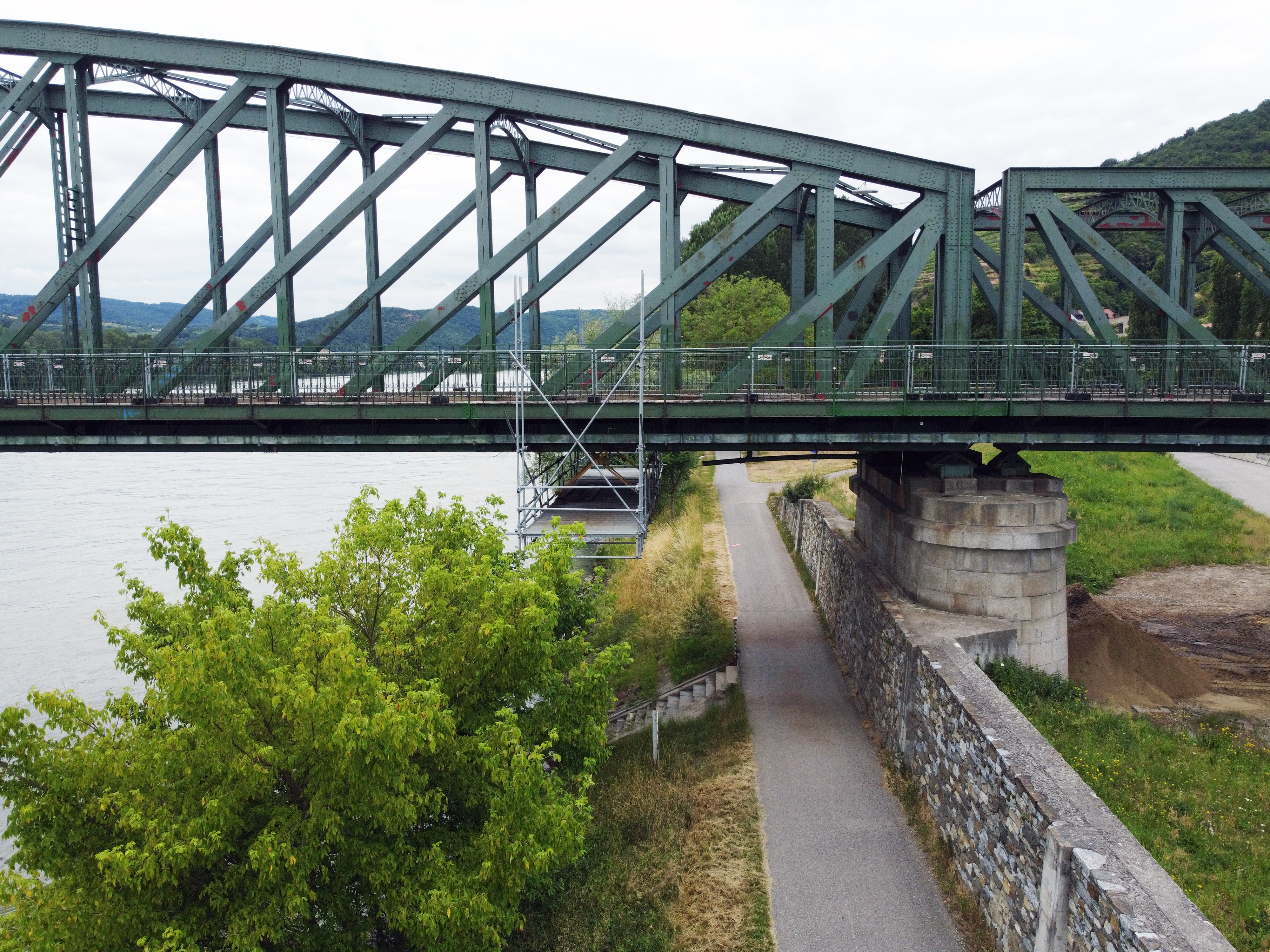 Drohnenaufnahme der Donaubrücke Stein-Mautern von schräg oben, mit Pfeiler, Arbeitsplattform, Uferweg und der Wachau im Hintergrund.